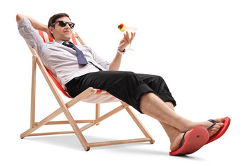 Businessman with a cocktail relaxing in a deck chair