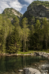 Fototapeta na wymiar Italia: il lago alpino della Val di Mello, una valle verde circondata da montagne di granito e boschi, ribattezzata la Yosemite Valley italiana dagli amanti della natura
