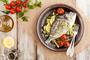 Baked whole fish, served with roasted vegetables and lemon.