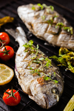 Grilled whole fish, served with roasted vegetables and lemon.