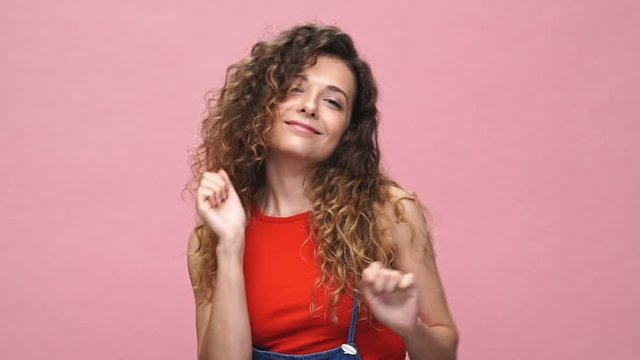 Young happy caucasian lady dancing over pink background