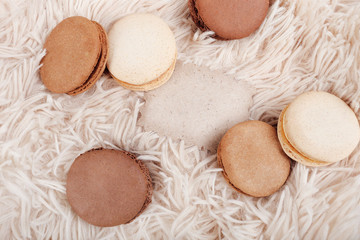 Macarons with paper blank copy space. Macarons of coffee color on a soft background, with a blank for a design.
