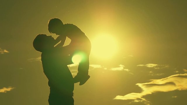 Father and son playing in the park at sunset silhouette of a happy family