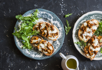 Mushrooms  tartine. Baked sandwiches with mushrooms chanterelles and mozzarella on a dark background, top view