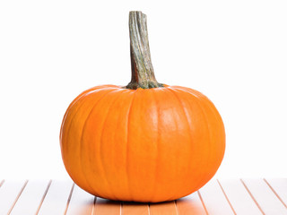Fresh orange pumpkin on table, isolated on white background. Studio shot of a nice ornamental autumn pumpkin for Halloween.