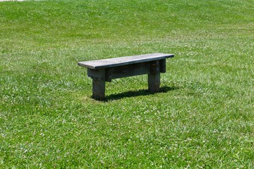 The small wood park bench in the green grass.