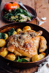 Whole roasted chicken with potatoes on dinner table