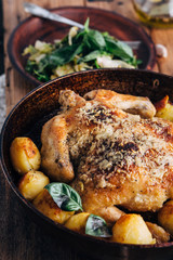 Whole roasted chicken with potatoes on dinner table