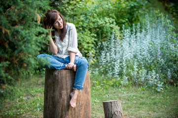 young girl is sitting on the stump