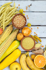Composition of yellow vegetables, beans and fruits - banana, corn, lemon, plum, apricot, pepper, zucchini, tomato, asparagus bean, millet, soybeans, peas, ginger. Healthy food. Top view. Flat lay