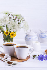 Cup of coffee tea chicory drink hot beverage  with chicory flower and sugar cookies on a white table.  Still life with breakfast