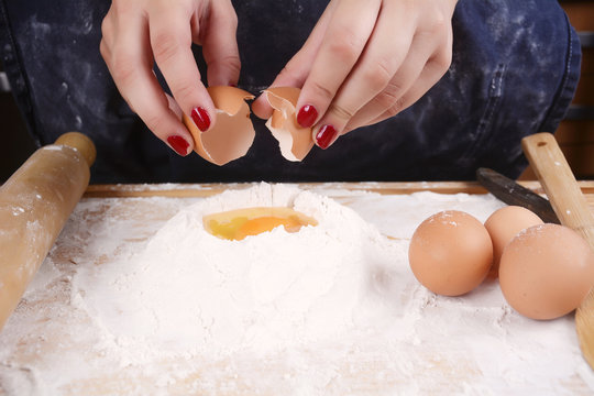Woman breaking an egg.