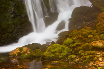 waterfall among rocks covered with green moss
