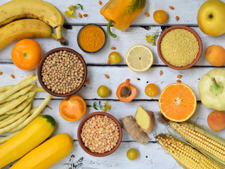 Composition of yellow vegetables, beans and fruits - banana, corn, lemon, plum, apricot, pepper, zucchini, tomato, asparagus bean, millet, soybeans, peas, ginger. Healthy food. Top view. Flat lay