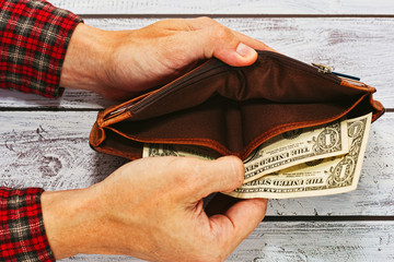 Man in work shirt holding wallet with just two dollars