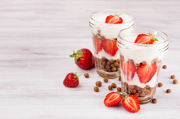 Breakfast with chocolate balls corn flakes, sliced strawberry in jars on white wood board. Decorative border with copy space.
