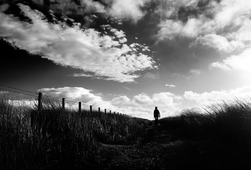 A black and white image of a hiker exploring the English Countryside, Muggleswick Common near Edmundbyers, England UK.