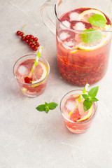 Red currant  lemonade in a glass jar on slate, concrete background.