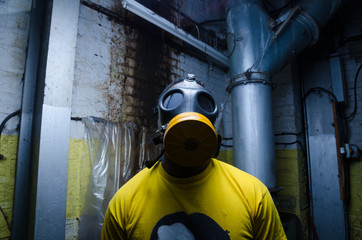 A scary man with reflection eyes in an industrial setting wearing a horror gas mask staring and intimidating. A horror movie character.