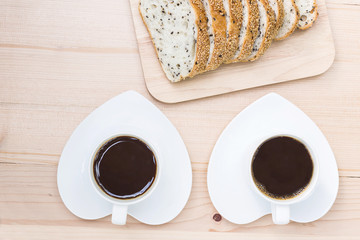 Two coffee cup with bread on wooden background