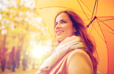 happy woman with umbrella walking in autumn park