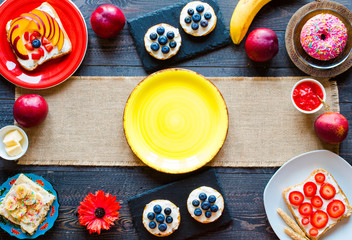 Delicious healthy breakfast, fruit sandwiches with different fillings, cheese, banana, strawberry, fishing, butter, blueberry, on a different wooden background.