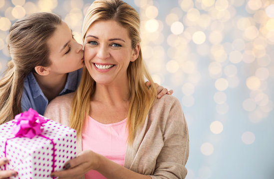 girl giving birthday present to mother over lights