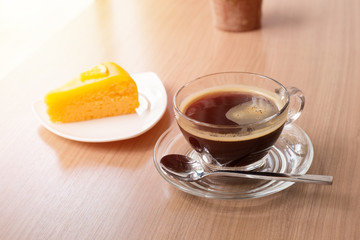 Black coffee and orange cake on wooden table