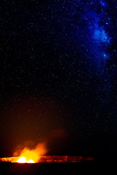 Ein Lavasee im  Halemaumau Krater auf dem Kilauea beleuchtet aufsteigende vulkanische Dämpfe vor der Milchstraße im Nachthimmel im Hawaii Volcanoes National Park auf Big Island, Hawaii, USA.