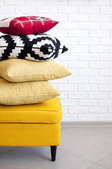 Yellow puff with pillows against a white brick wall. Concept Interior Things Copy Space.