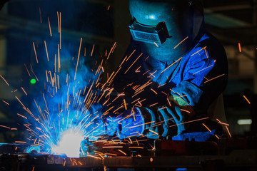 Industrial worker with protective mask is welding metal .
