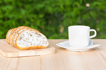 White coffee cup and sliced bread on wooden table