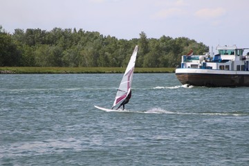 Windsurfer and transport ship sharing the river