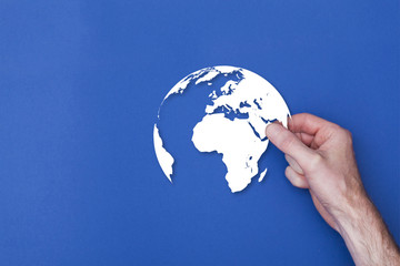 male hand holding a world globe icon symbol against a blue background