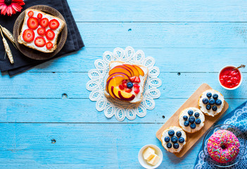 Fototapeta na wymiar Delicious healthy breakfast, fruit sandwiches with different fillings, cheese, banana, strawberry, fishing, butter, blueberry, on a different wooden background.