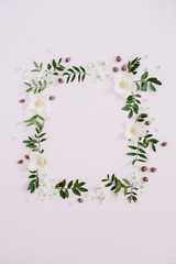 Frame of flowers, branches, leaves and petals with space for text on pink background. Flat lay, top view