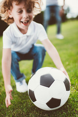 close-up view of happy little boy playing with soccer ball at park