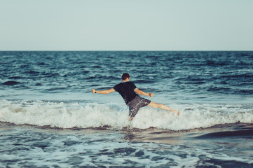 A young man is jumping and having fun in the sea