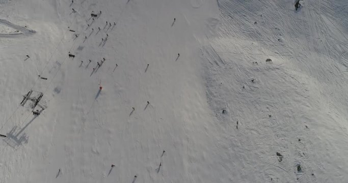 aerial drone footage  flying over skiing slopes  crowded with skiers  on beautiful slopes at  fresh snow on beautiful winter day