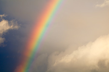 Beautiful rainbow after rain in the blue cloudy sky