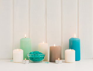 Fototapeta na wymiar Spa composition. Spa candles, sea salt, turquoise towels on rustic white wooden background.