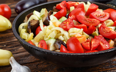 Sliced fresh vegetables in pan with spices and ingredients on wo