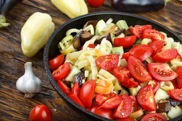 Sliced fresh vegetables in pan with spices and ingredients on wo