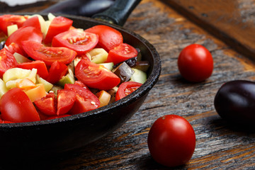 Sliced fresh vegetables in pan with spices and ingredients on wooden table