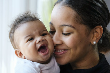 Close up portrait of a African American woman holding a baby girl - obrazy, fototapety, plakaty