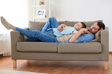 happy father and son sleeping on sofa at home