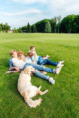 Obraz premium happy young family with golden retriever dog resting on grass at picnic