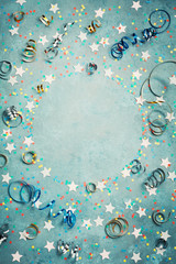 Party, carnival or birthday frame with colorful confetti and streamer on vintage blue table top...