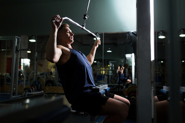 man flexing muscles on cable machine in gym