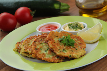 Vegetable zucchini pancakes served with yogurt and tomato sauce. Ingredients for cooking on background. Close up view.